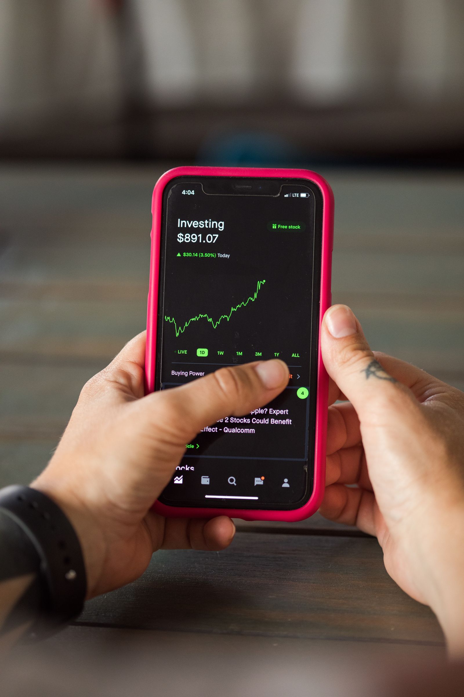 Hands holding a smartphone running a stock-investing app