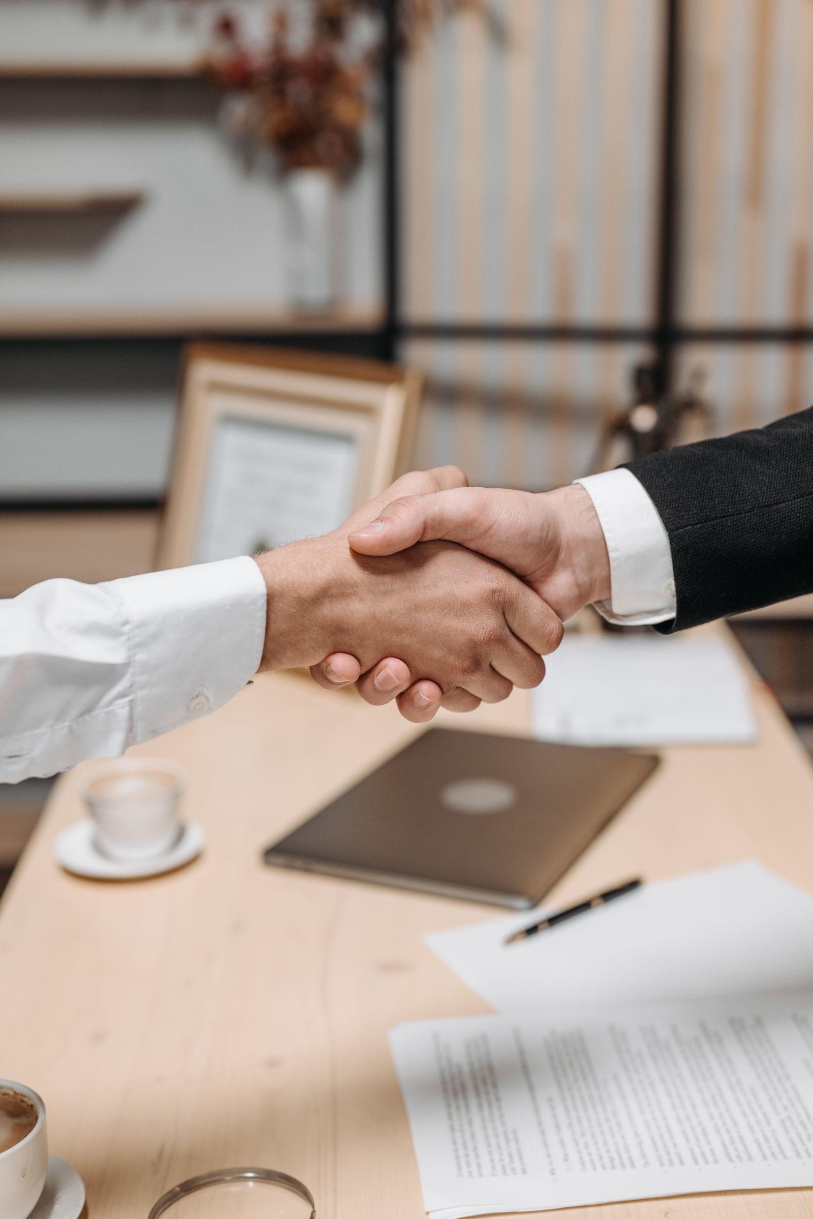 Two people shaking hands across an office desk