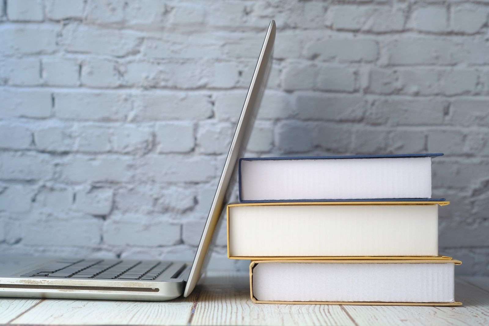 A laptop resting against a stack of books