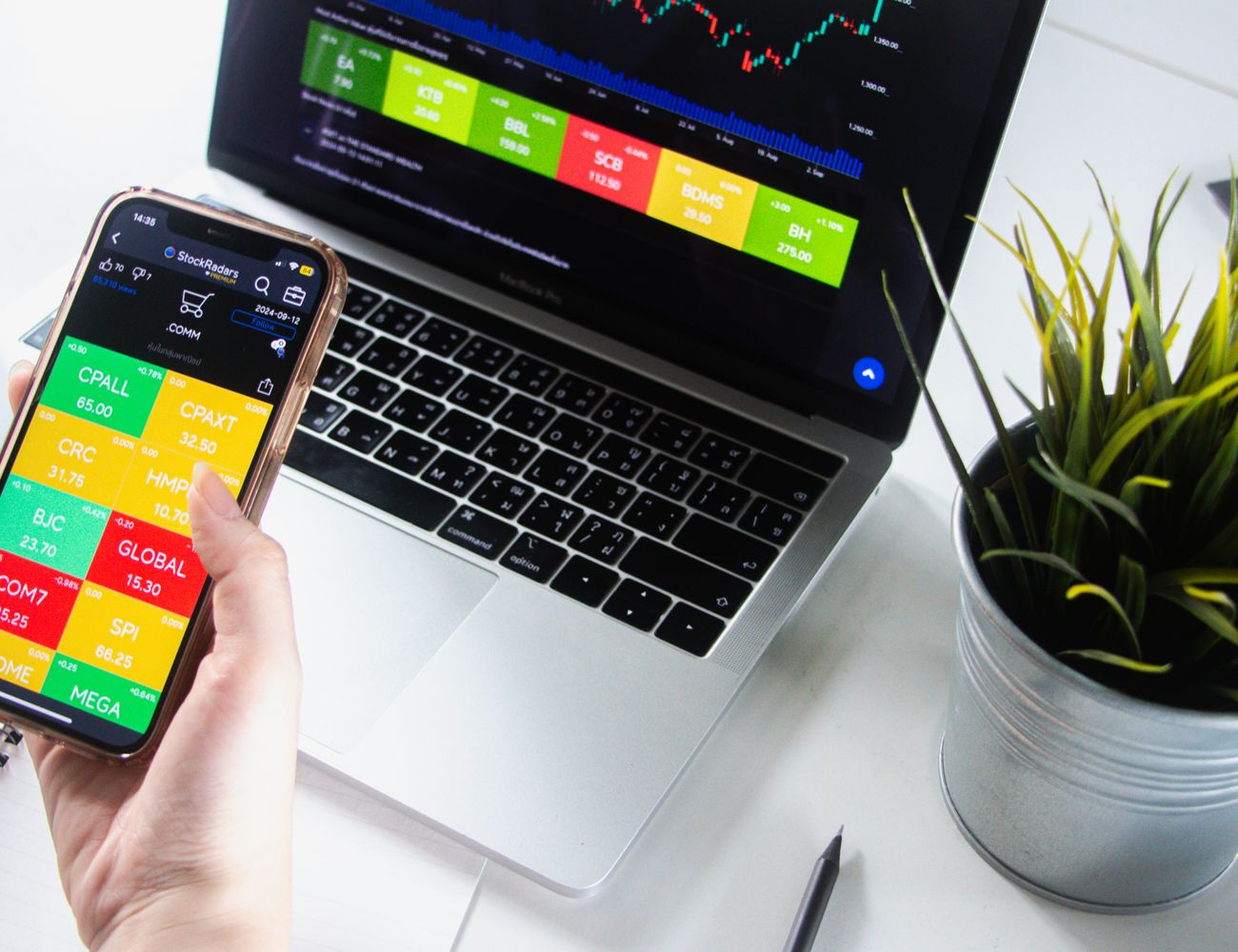 Trading in a browser on a laptop beside a phone