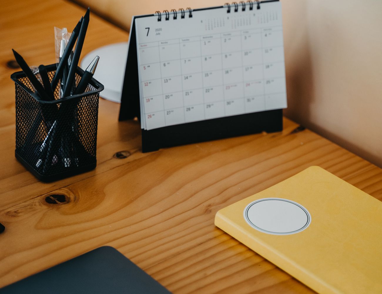 A desk calendar and planner beside a laptop